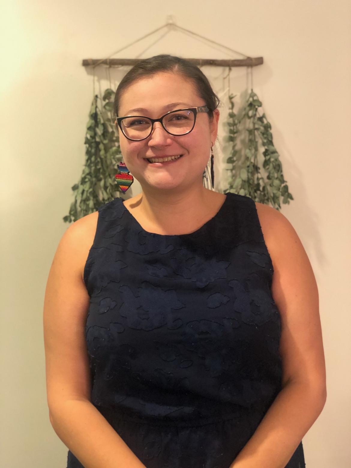 Therapist Juliana Carranza wearing a black sleeveless and glasses smiling at the camera 