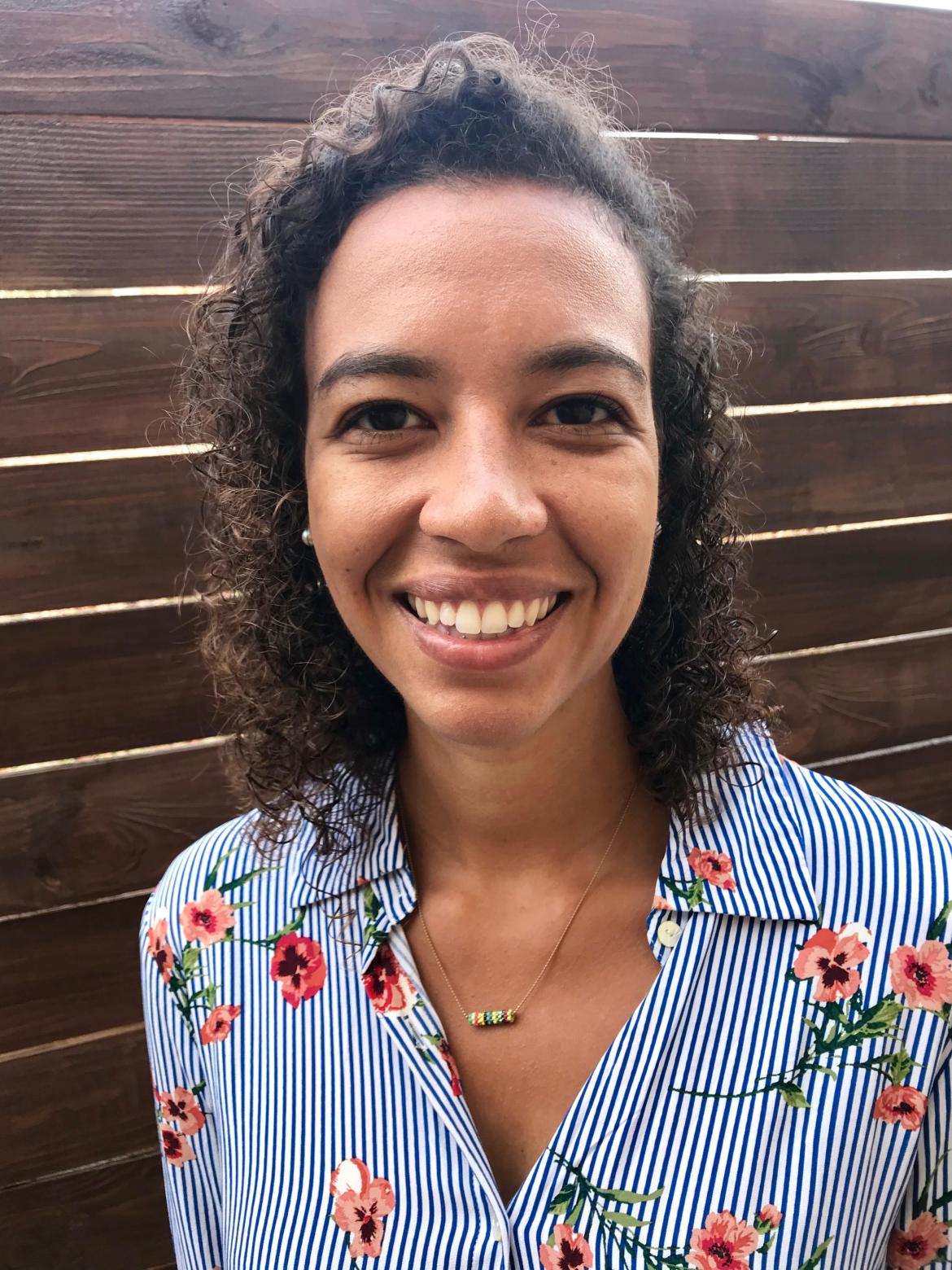 Therapist Nicole Hayes wearing a blue and white striped shirt with red flowers on it smiling at the camera