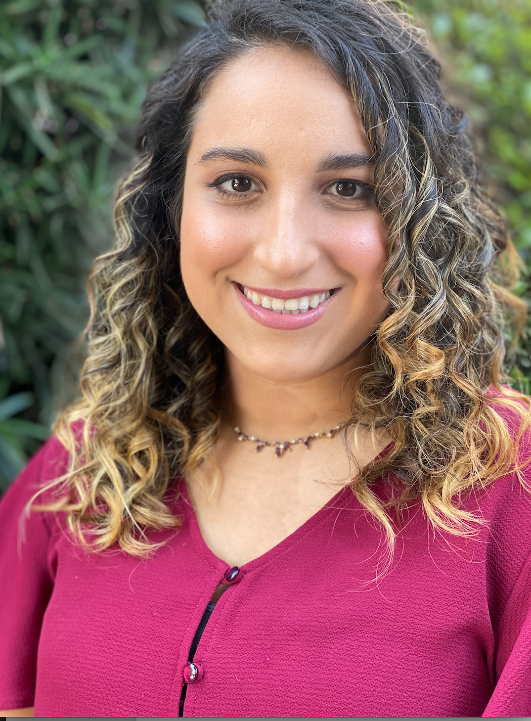Therapist Tara Tehrani wearing a magenta button up shirt smiling at the camera