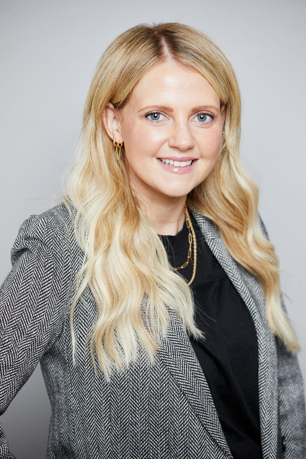 Therapist Lauren Jensen smiling at the camera wearing a gray blazer and a black shirt