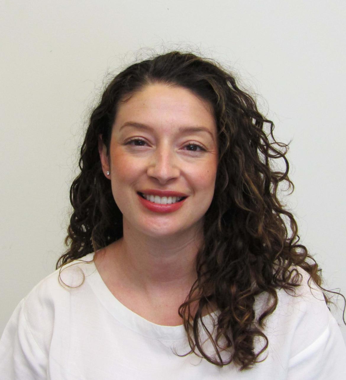 Therapist Yadira Anguiano smiling at the camera wearing a white shirt in front of a white background