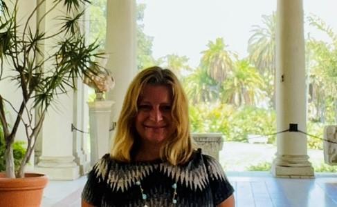 Therapist Johanna Slivinske wearing a black and white shirt with a potted plant next to her and smiling at the camera 