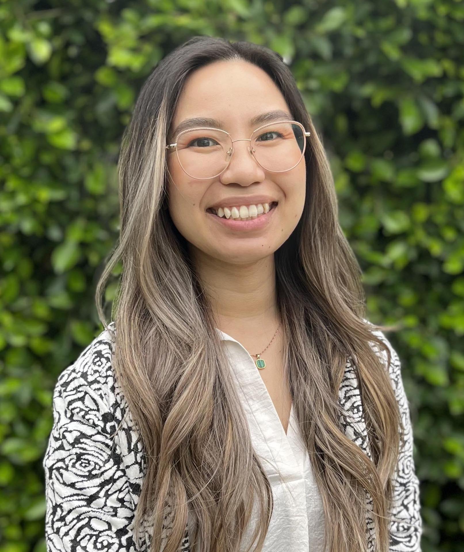 Intern Tarm wearing a black and white cardigan over a white shirt smiling at the camera 