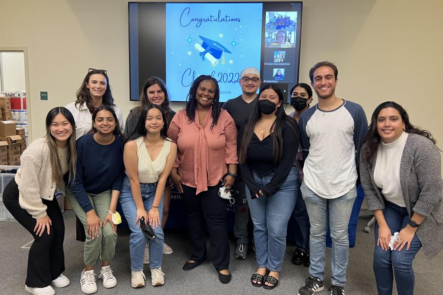 BMHAC team smiling at the camera posing in front of a screen that says Congratulations class of 2022 with Dr. Nicole Green in the center